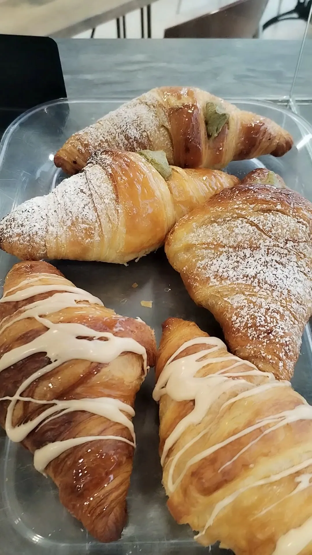 Croissants con azúcar glas y croissants con glaseado blanco en una bandeja