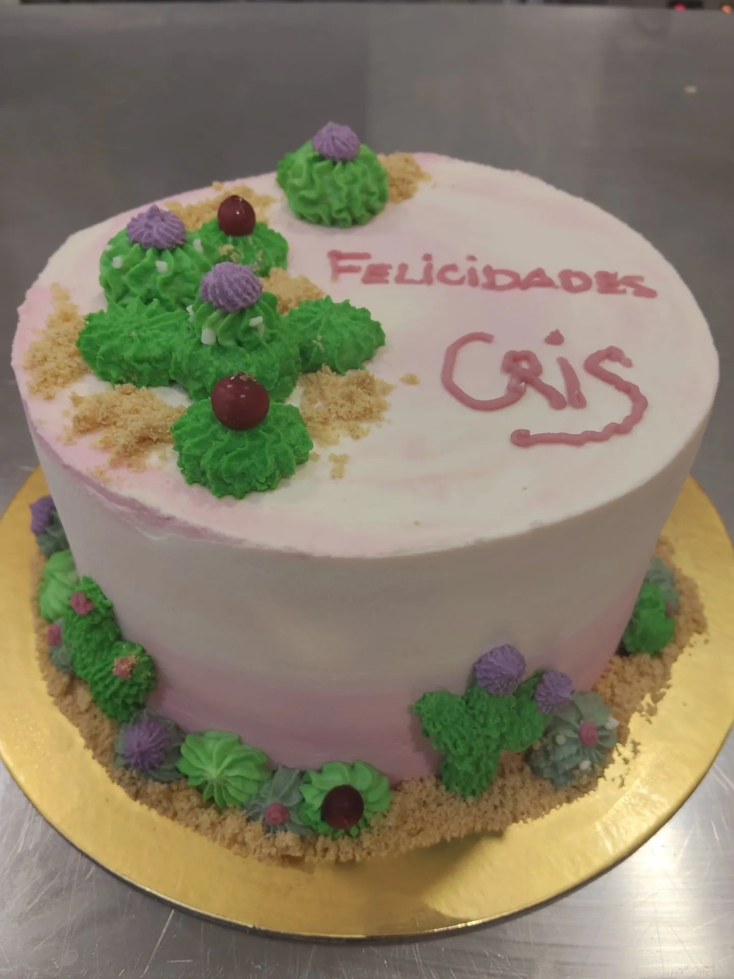Tarta rosa decorada con cactus de crema verde y la palabra Felicidades